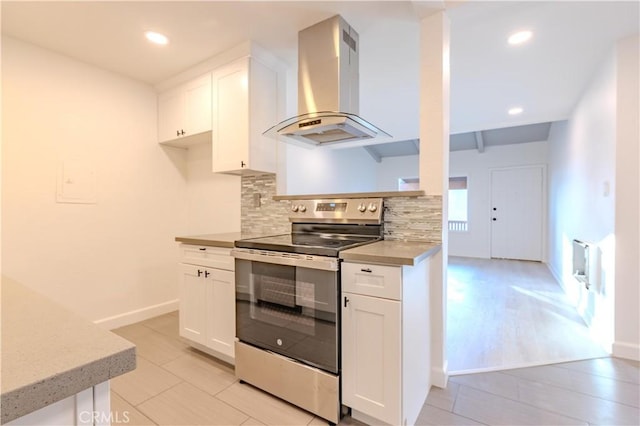 kitchen featuring light tile patterned floors, island exhaust hood, decorative backsplash, stainless steel electric stove, and white cabinets