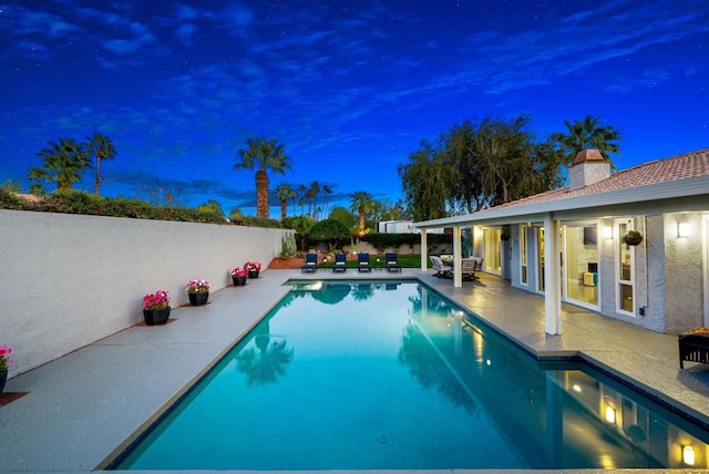 pool at dusk with a patio area