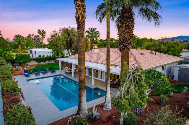 pool at dusk with a patio area