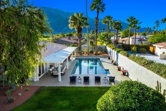 view of pool with a patio, a yard, and a mountain view