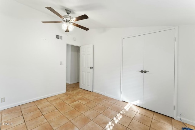 unfurnished bedroom with light tile patterned flooring, lofted ceiling, ceiling fan, and a closet