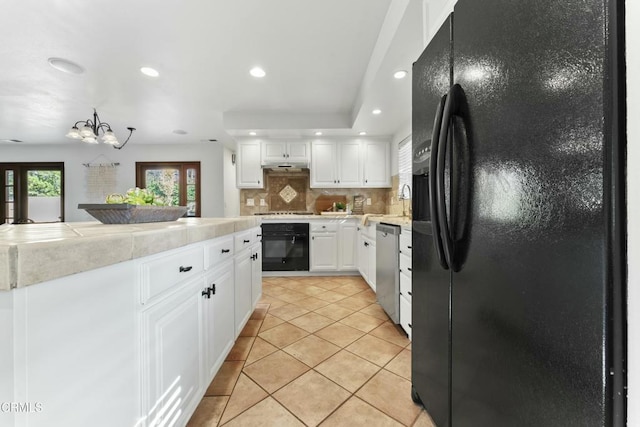 kitchen featuring black appliances, a chandelier, light tile patterned floors, white cabinets, and backsplash