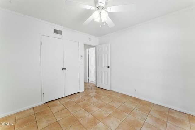 unfurnished bedroom with ornamental molding, light tile patterned flooring, ceiling fan, and a closet