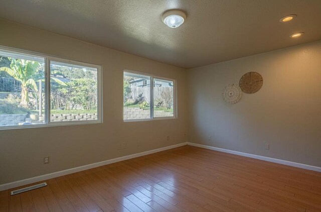 unfurnished room with wood-type flooring and a textured ceiling