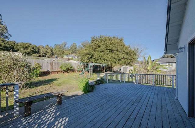 deck with a lawn, a storage shed, and a playground