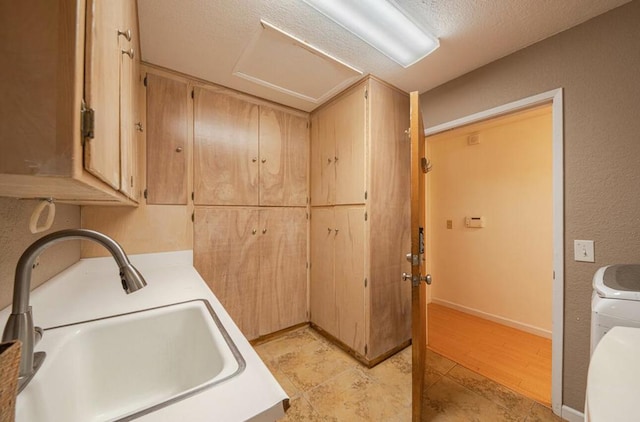 laundry room with sink, a textured ceiling, light tile patterned floors, and washer / clothes dryer