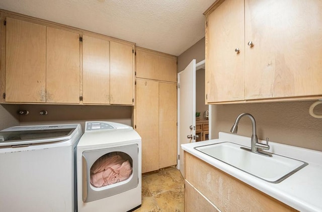 laundry area with independent washer and dryer, sink, a textured ceiling, and cabinets