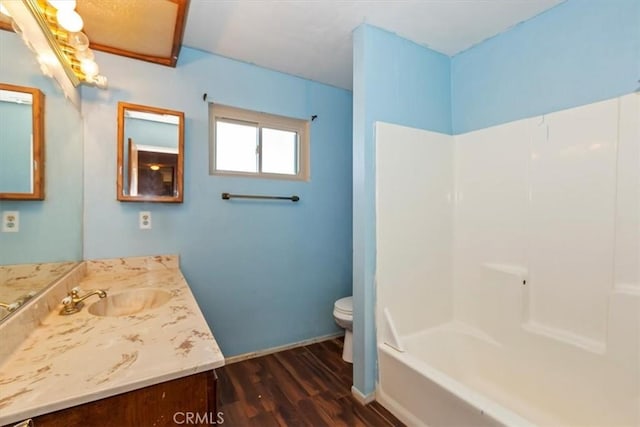 full bathroom with toilet, hardwood / wood-style floors, vanity, and washtub / shower combination