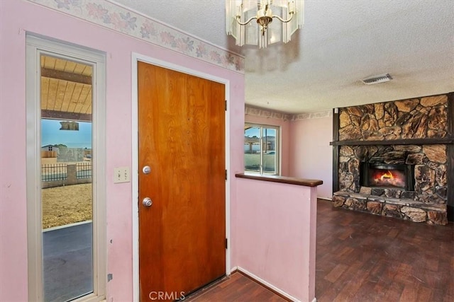 entryway with a textured ceiling, dark hardwood / wood-style floors, and a stone fireplace