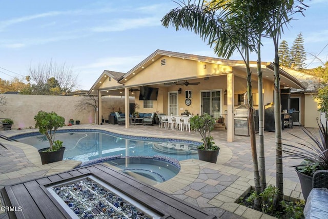 view of pool featuring ceiling fan, a patio, an in ground hot tub, and exterior kitchen