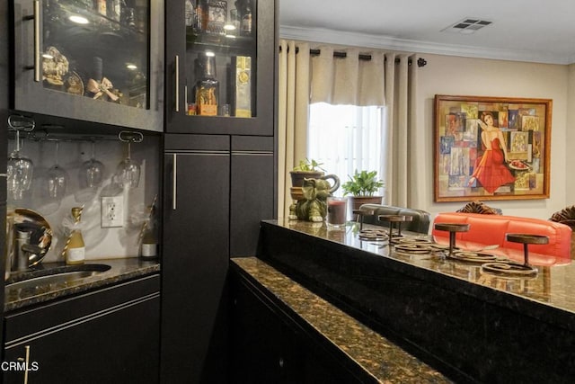 bar with sink, dark stone countertops, and crown molding