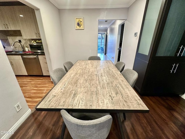 dining room featuring sink, dark hardwood / wood-style flooring, and crown molding