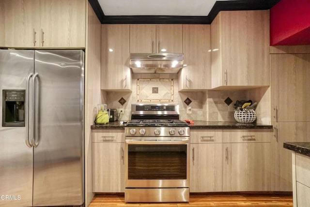 kitchen featuring appliances with stainless steel finishes, dark stone countertops, light brown cabinetry, and backsplash