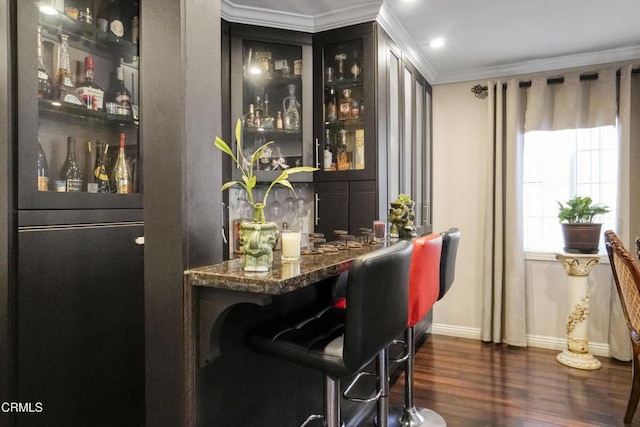 bar with dark stone counters, crown molding, and dark hardwood / wood-style floors