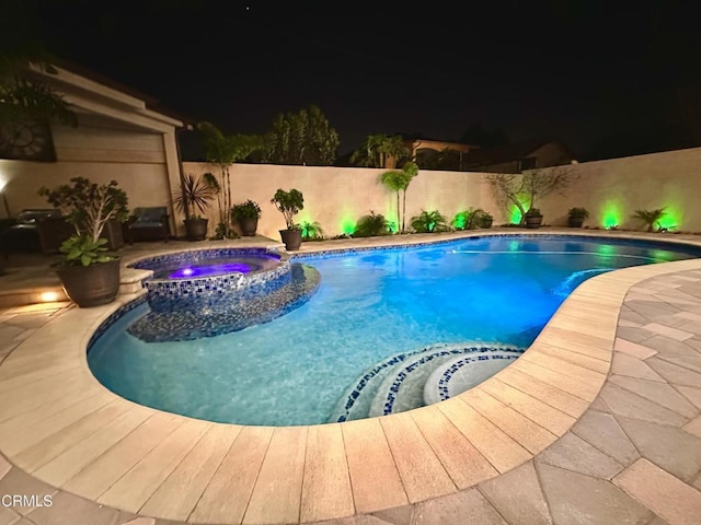 pool at twilight featuring an in ground hot tub and a patio area