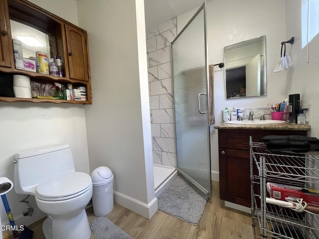 bathroom with a shower with shower door, hardwood / wood-style floors, toilet, and vanity