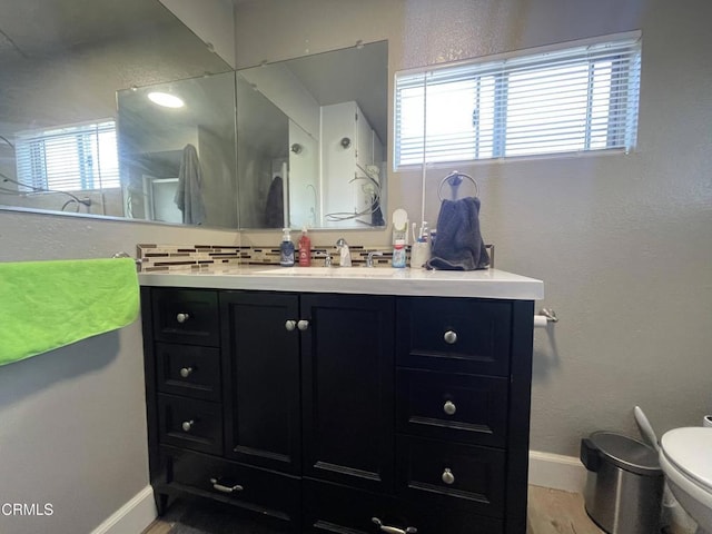 bathroom with toilet, vanity, decorative backsplash, and wood-type flooring