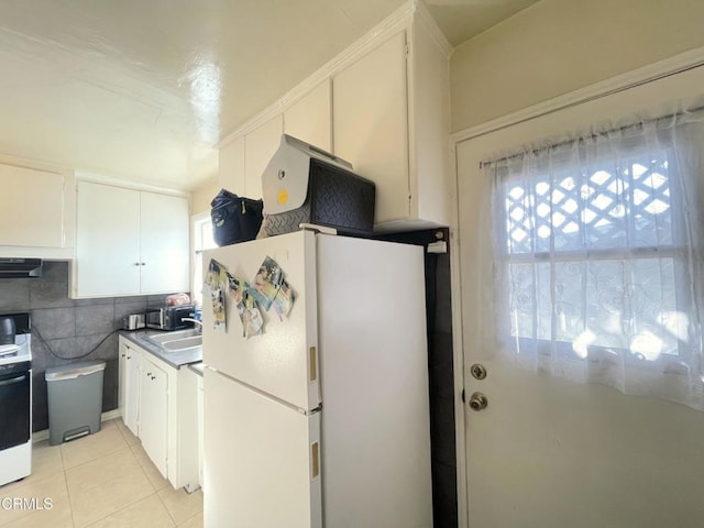 kitchen featuring white fridge, decorative backsplash, sink, light tile patterned floors, and white cabinets