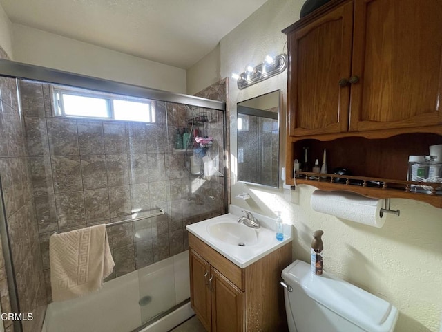 bathroom featuring toilet, vanity, and a shower with door