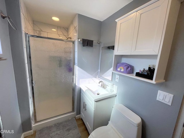 bathroom featuring toilet, a shower with shower door, hardwood / wood-style flooring, and vanity