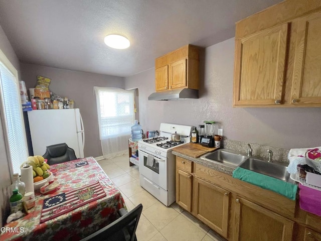 kitchen featuring sink, white appliances, light tile patterned floors, and a textured ceiling