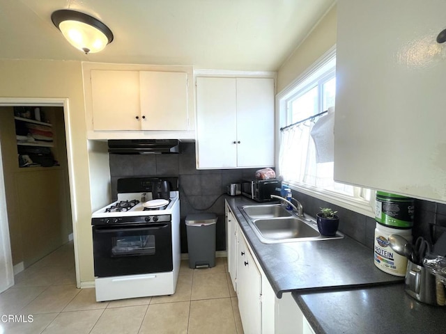 kitchen with light tile patterned floors, ventilation hood, gas range, white cabinets, and sink