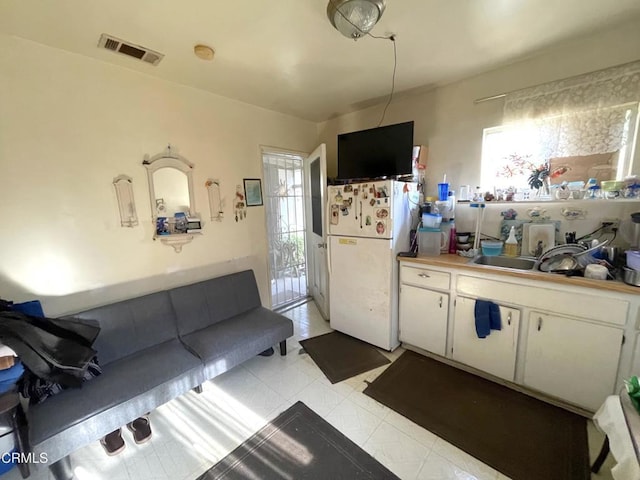 kitchen featuring sink, white fridge, and white cabinetry