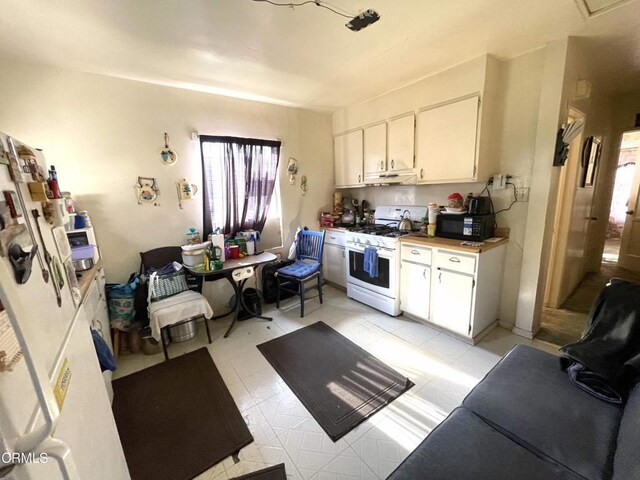 136 S Roosevelt Ave, Oxnard, CA 93030 - kitchen featuring white gas range, black microwave, white cabinets, light countertops, and under cabinet range hood