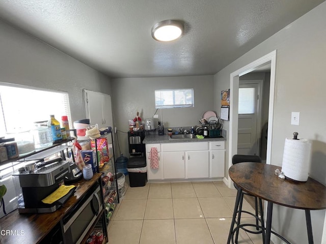 136 S Roosevelt Ave, Oxnard, CA 93030 - kitchen featuring stainless steel microwave, white cabinets, a textured ceiling, and light tile patterned floors