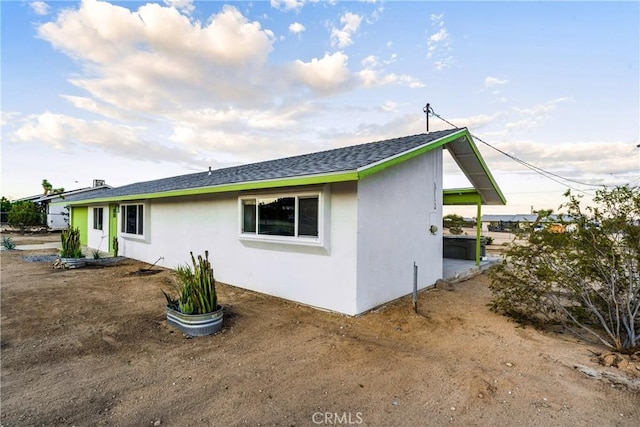 view of property exterior featuring stucco siding and roof with shingles