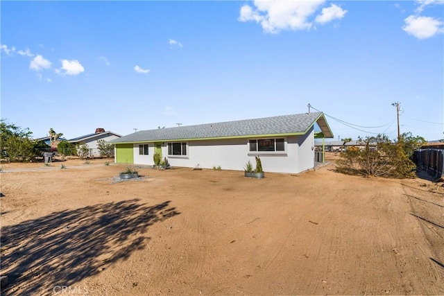 back of property with stucco siding and fence