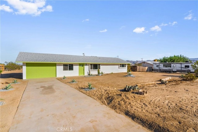 ranch-style house featuring stucco siding, an attached garage, concrete driveway, and fence