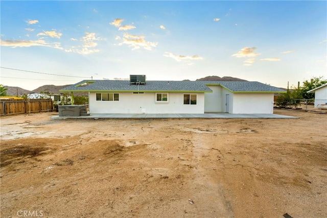 rear view of property featuring stucco siding, central air condition unit, a patio, fence, and a hot tub