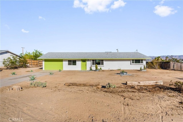 rear view of property with stucco siding and fence