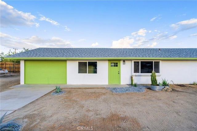 ranch-style home with an attached garage, fence, driveway, and stucco siding