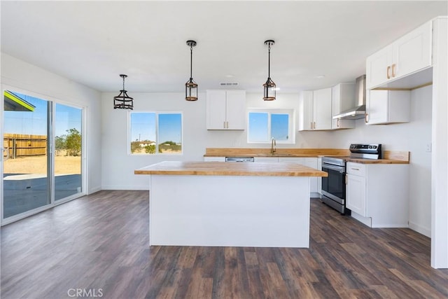 kitchen with a sink, a center island, wall chimney exhaust hood, stainless steel electric range oven, and a healthy amount of sunlight