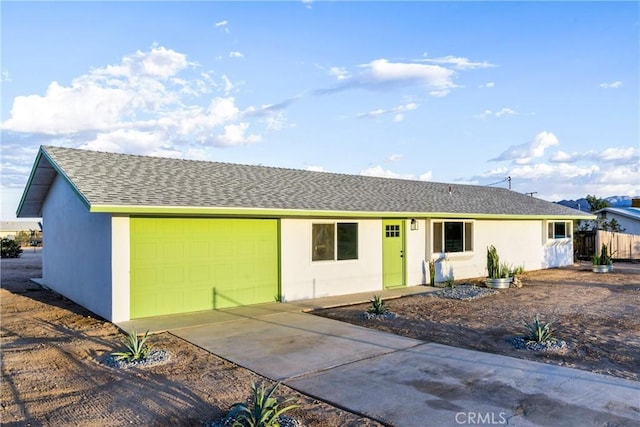 single story home with stucco siding, concrete driveway, a garage, and roof with shingles