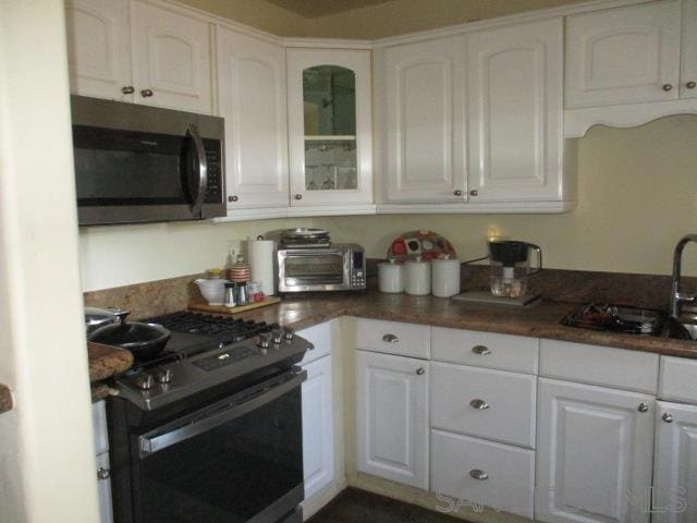 kitchen featuring appliances with stainless steel finishes, white cabinets, sink, and butcher block counters