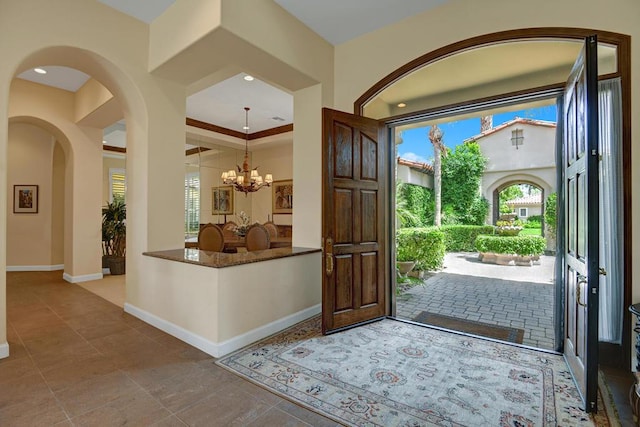 foyer entrance with an inviting chandelier and crown molding