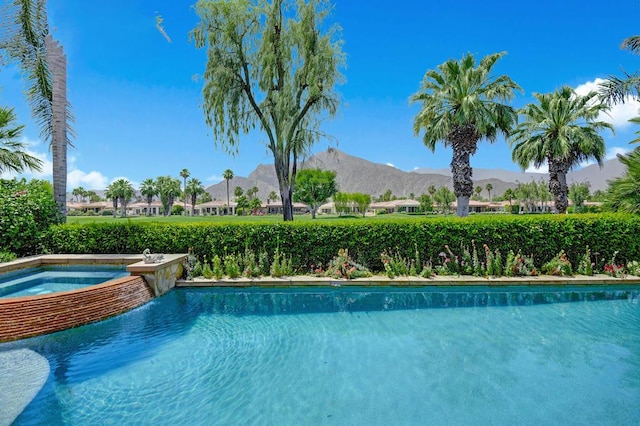 view of swimming pool with a mountain view and an in ground hot tub