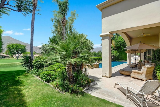 exterior space with ceiling fan, an outdoor living space, a patio area, a mountain view, and a yard