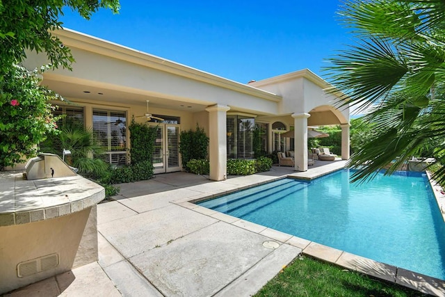 view of swimming pool with ceiling fan, an outdoor kitchen, and a patio