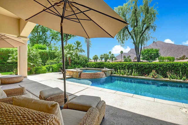 view of pool featuring a patio area, a mountain view, and an in ground hot tub