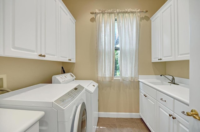 laundry area featuring washing machine and dryer, cabinets, light tile patterned floors, and sink