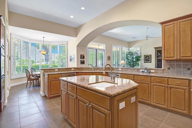 kitchen featuring decorative light fixtures, sink, kitchen peninsula, and a kitchen island with sink