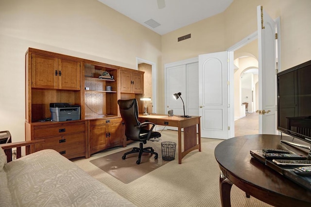 home office with light carpet and a towering ceiling