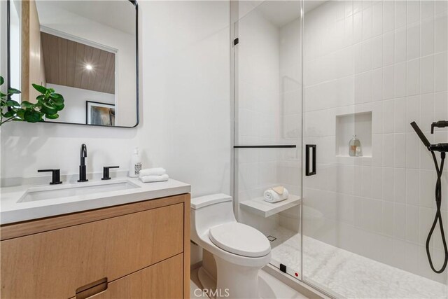 bathroom featuring toilet, a shower with shower door, and vanity