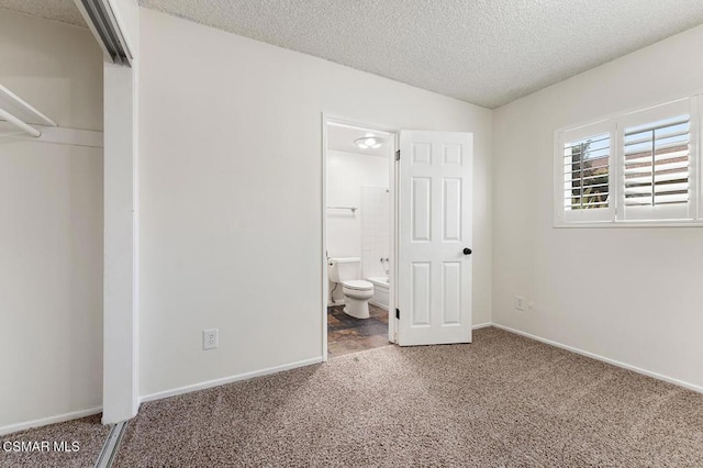 unfurnished bedroom with a textured ceiling, connected bathroom, and carpet