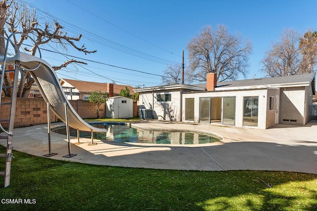 back of property with a fenced in pool, a patio, and a shed