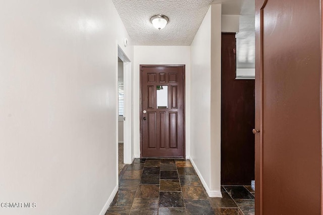 doorway to outside with a textured ceiling